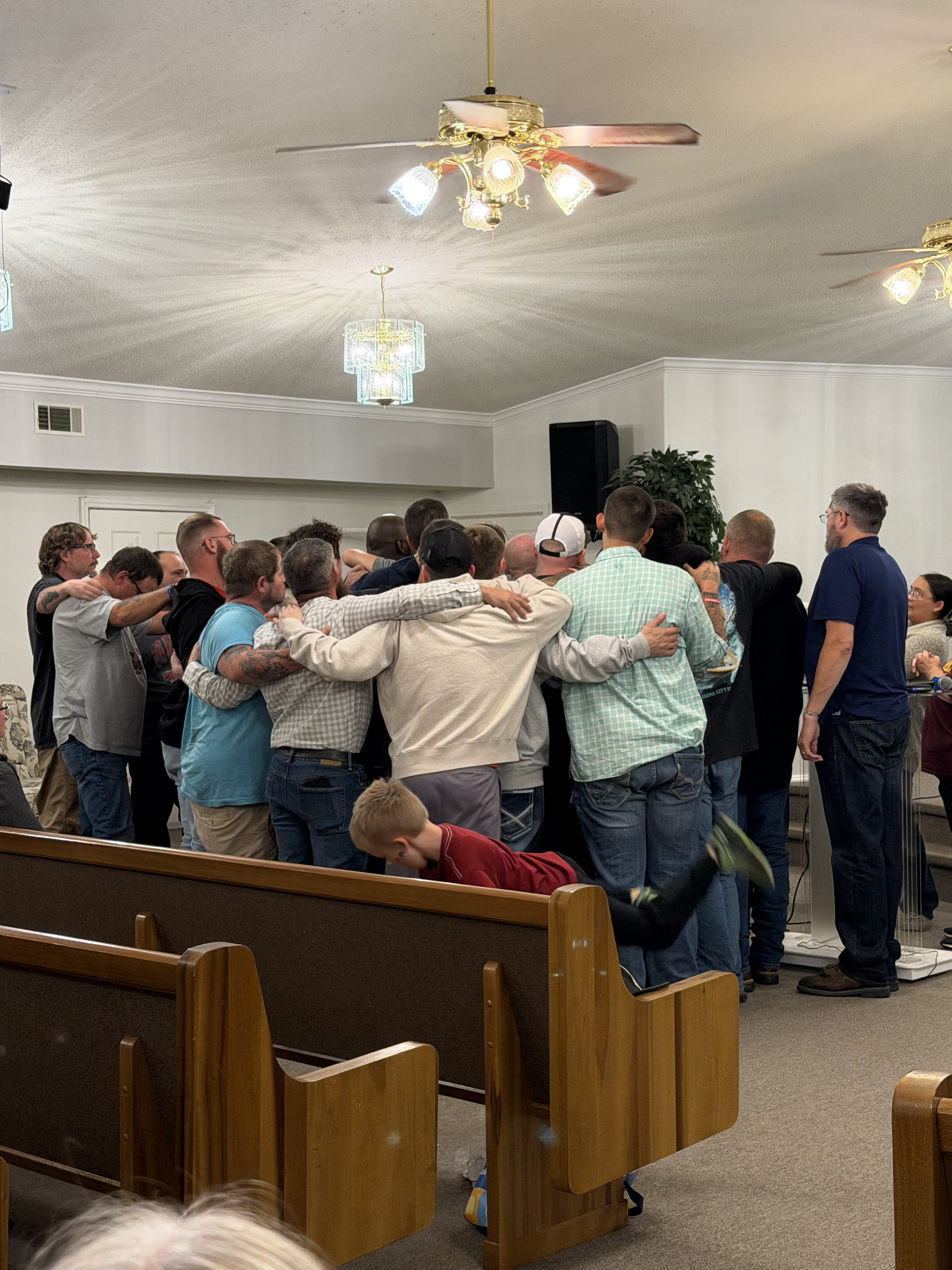 Men gathered in a circle praying together during a church service